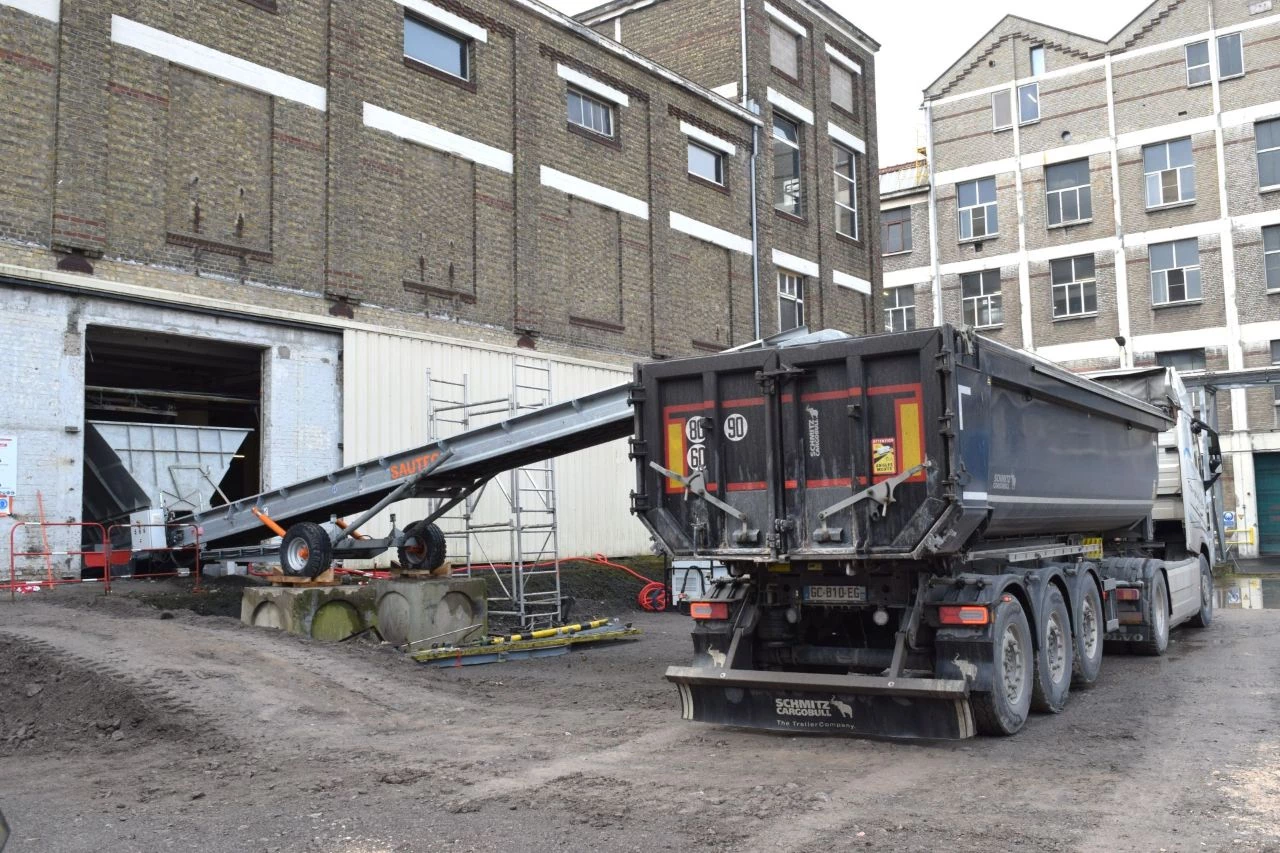 Un tapis transporteur utilisé sur un chantier pour évacuer les gravats dans la benne d'un camion.